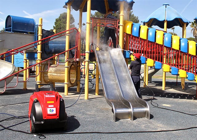 Two people using one Optima Steamer DMF to clean playground equipment