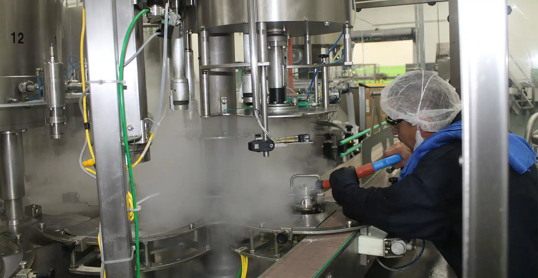 worker using optima steamer to clean food processing equipment